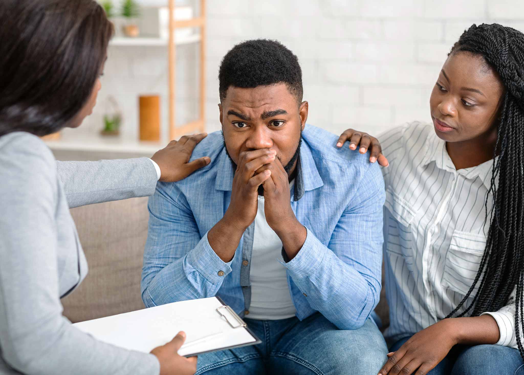 Therapist with her hand on the shoulder of a young man as she explains how addiction affects families