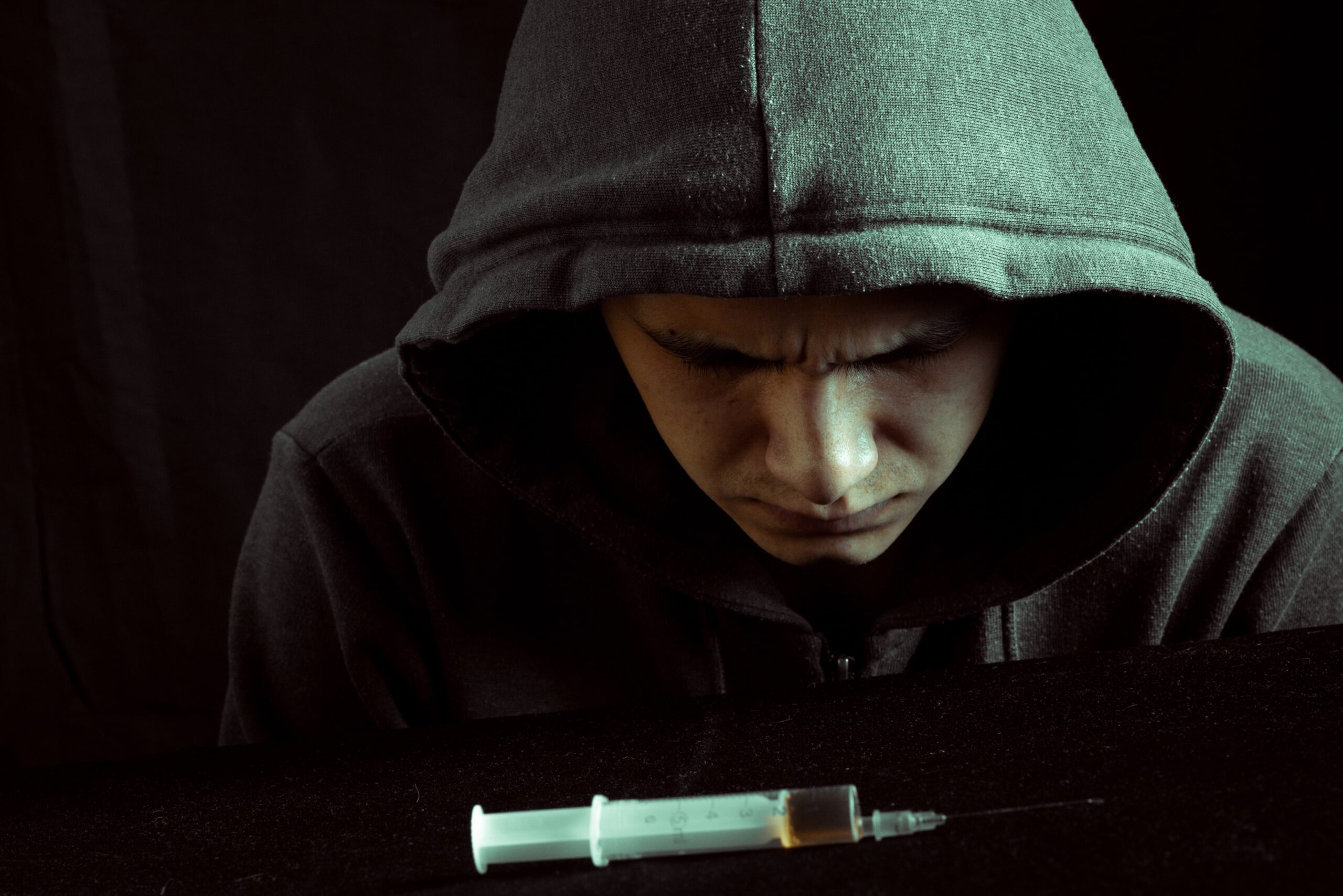 image of a young man next to a syringe concerning an adult son relapse