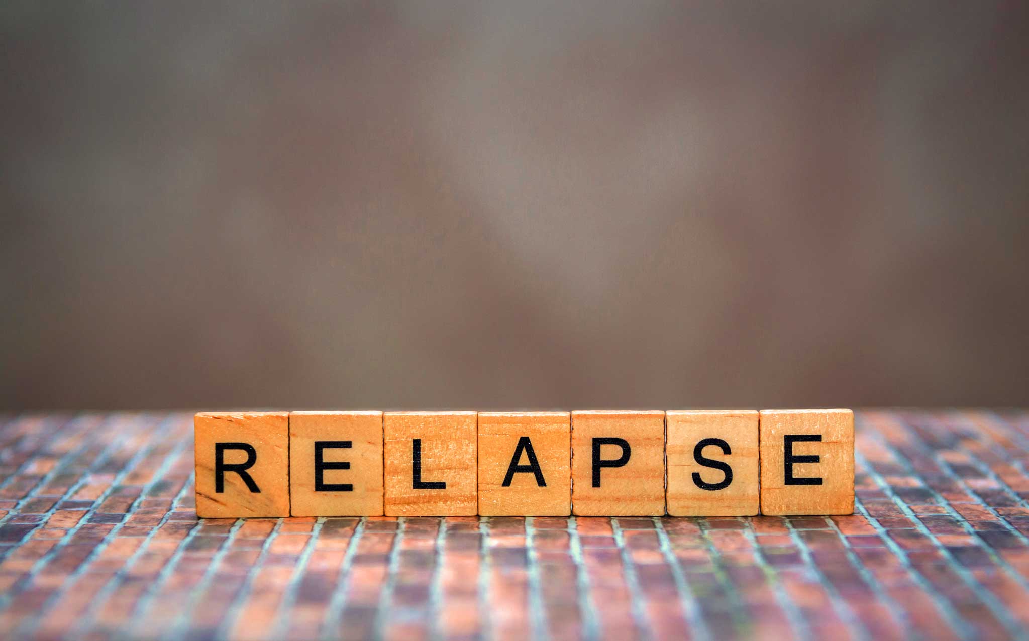 wood letter blocks spelling out relapse prompting the question: What does it mean to relapse?
