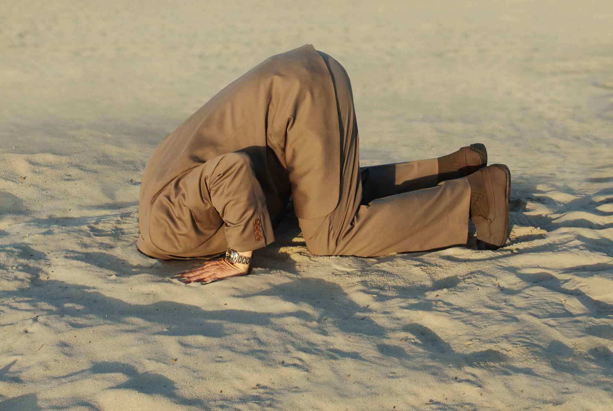 a man sticking his head in the sand as a representation of enabling addiction