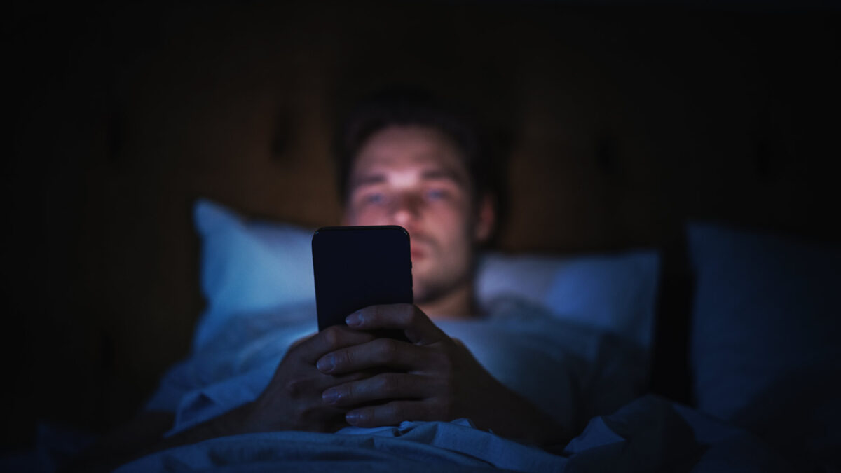 young man doom scrolling on his phone exhibiting signs of social media addiction